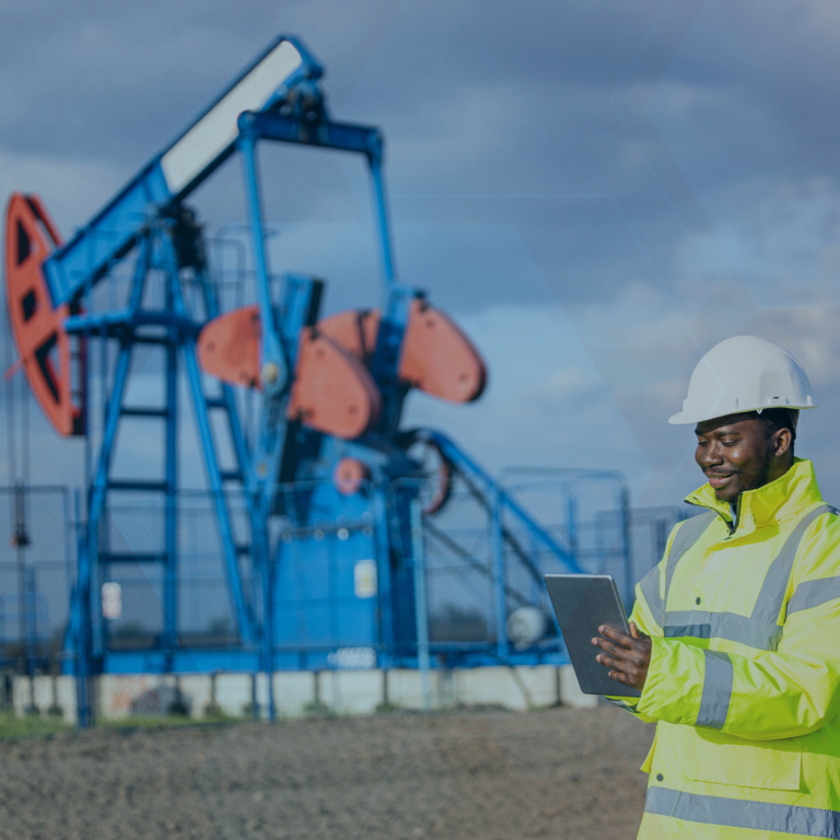 Predictive Maintenance in Oil and Gas - Man stands in front of oil refinery equipment smiling at clip board.